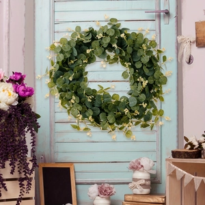 Green eucalyptus leaf wreath with small yellow buds hanging on a blue vintage farmhouse door