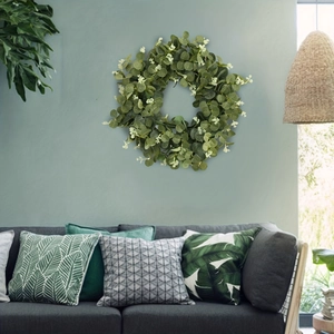 Green eucalyptus money leaf wreath with white buds hanging on a blue living room wall