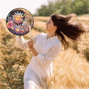 Detail of bohemian shaman drum with sun and moon pattern in a golden wheat field