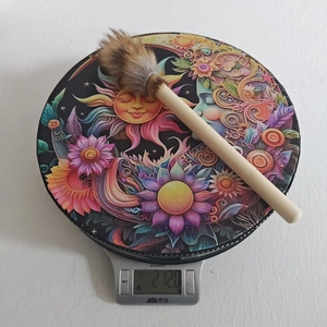 Detail shot of a handmade shaman drum weighing 212 grams on a scale with artistic patterns
