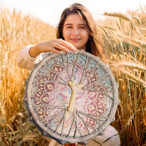 Handmade shamanic sun goddess drum with bohemian pattern in a warm autumn field
