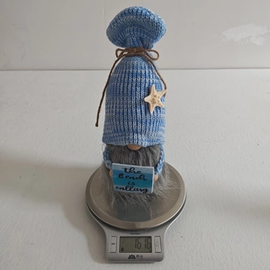 Detail of beach gnome holding a 'beach is calling' sign on a digital scale
