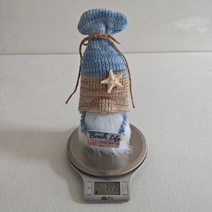 Blue beach gnome plush decoration weighing 147.9g on a scale for product measurement