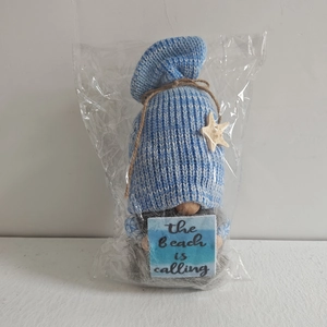 Detail of beach gnome plush with starfish hat and The Beach is Calling wooden sign