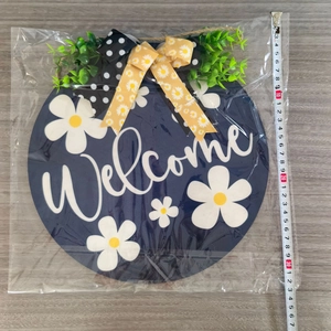 Detail view of a 30cm wooden Welcome sign with white daisies and a decorative bow