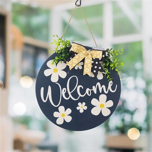 Detail of blue wooden Welcome sign with white daisies, green leaves and a floral bow