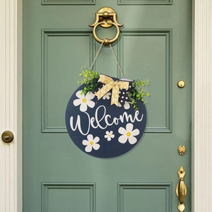 Detail of navy wooden welcome sign with daisies and bows on a sage green door