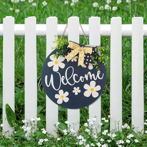 Close-up of a blue wooden welcome sign with a polka dot bow and green leaves on a fence