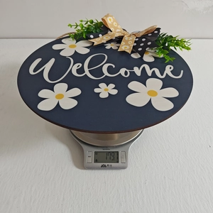 Detail view of welcome sign with white daisies and bow showing weight on digital scale