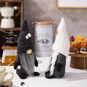Detail of two handmade coffee gnomes with knitted hats and miniature cups on table