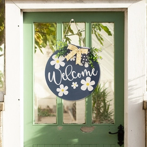 Blue wooden welcome sign with white daisies, floral bow, and greenery for front door
