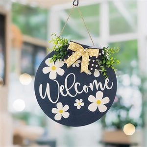 Navy blue wooden welcome sign with white daisies, floral bow, and green foliage decor