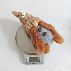 Macro shot of coffee gnome with brown knit hat on a digital scale for weight display