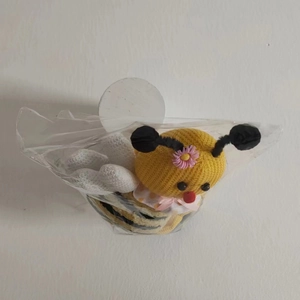 Detalle de sujetadores de cortinas tejidos a mano con forma de abeja y flores rosadas