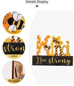 Detail display of Bee Kind and Bee Strong wooden ornaments with bee and daisy patterns