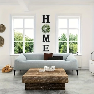 Modern home wall decor with black letters and artificial green wreath on white wall