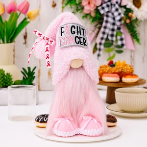 Gnome en peluche rose avec texte Fight Cancer et rubans roses sur une table décorée