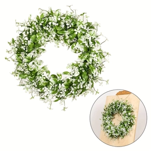 Detalle de corona de follaje verde artificial con pequeñas flores blancas decorativas