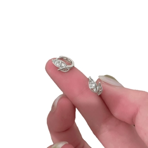 Silver leaf huggie earrings with sparkling zircon stones held for size comparison