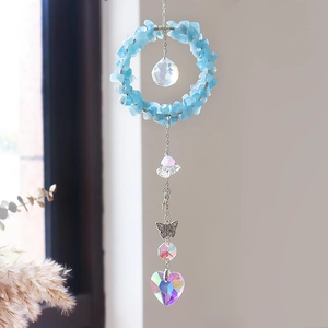 Detail van kristallen zonnevanger met blauwe stenen, vlinder en hartvormige hanger