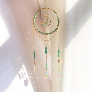 Detail of crystal sun catcher with gold crescent moon, green stones, and K9 prism