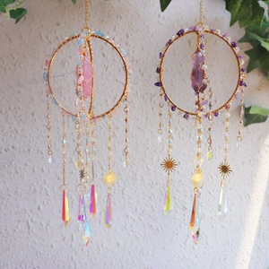 Detailed view of pink and purple crystal suncatchers with golden prisms and beads