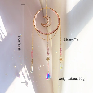Crystal suncatcher with pink quartz moon and golden rings casting rainbow light reflections