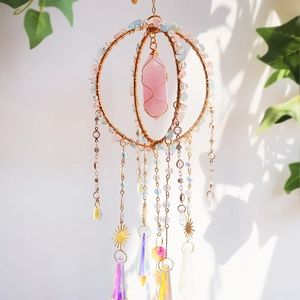Detail of bohemian sun catcher with rose quartz prism and golden metal crystal cage
