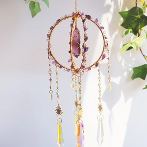 Detail of boho amethyst crystal suncatcher with golden chains and iridescent pendants