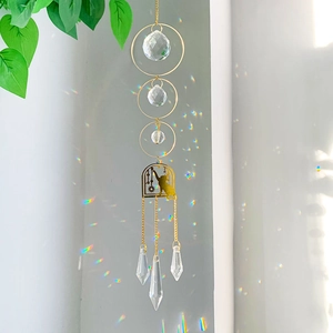 Detail of hanging suncatcher featuring crystal prisms and a golden cat arch design