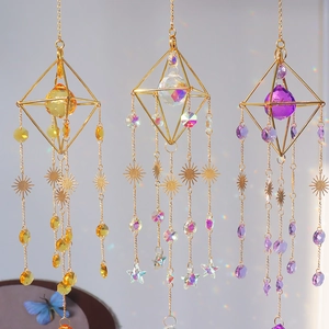 Close-up of three geometric crystal suncatchers in gold frames with rainbow prisms