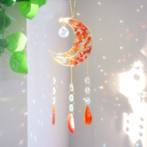 Detail of moon sun catcher with agate slices and crystal prism casting rainbow light