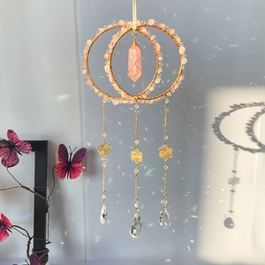 Detail of bohemian rose quartz suncatcher showing polished crystal prism and gold rings