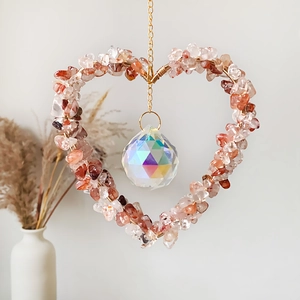 Primer plano de atrapasueños de corazón con piedras rojas y prisma de cristal