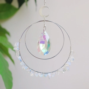 Detailed view of crescent moon crystal hanger with opal stones and iridescent pear pendant