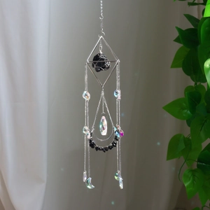 Λεπτομέρεια ασημένιου γεωμετρικού suncatcher με μαύρη πέτρα και κρυστάλλινα μενταγιόν