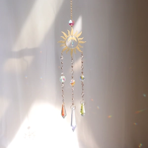 Detail of sun and moon crystal suncatcher reflecting rainbow light spots on a wall