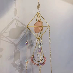 Detail of bohemian suncatcher with pink raw stone and geometric gold metal frame