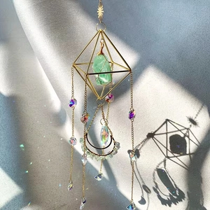 Detail of bohemian suncatcher with green raw stone and moon charm on silver satin