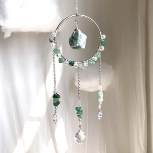 Close-up of bohemian sun catcher with green crystals and silver metal ring