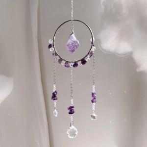 Detail of amethyst crystal suncatcher with silver rings and iridescent star pendants
