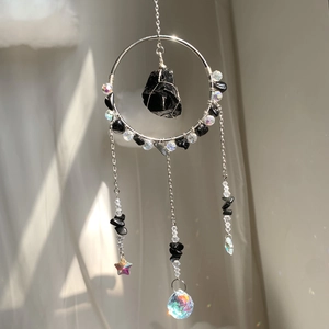 Detail of sun catcher featuring black raw gemstone and crystal ball for rainbow light