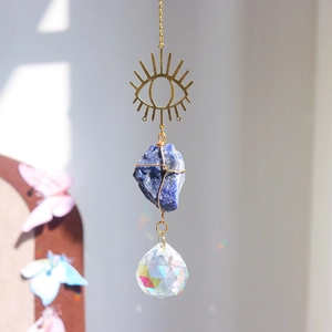 Detail of evil eye suncatcher with blue raw stone casting rainbow light on wall