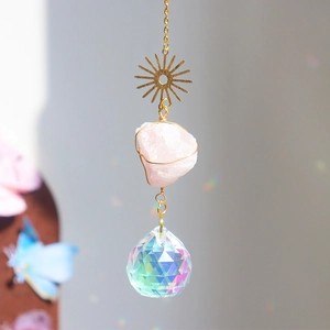 Detail of sun catcher featuring raw pink quartz stone and multifaceted crystal ball pendant