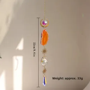 Macro detail of agate suncatcher with golden moon and sun ornaments and crystal prism