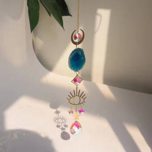 Detail of moon suncatcher with blue agate slice and crystal drops on golden chain