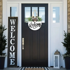 Close-up of a white circular welcome sign with a buffalo plaid bow and greenery