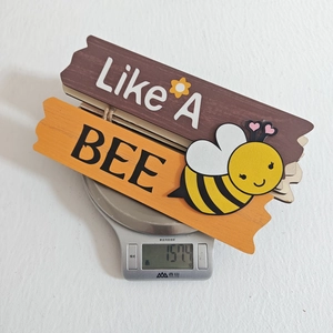 Dettaglio dell'insegna in legno per porta con testo Like A BEE e piccola ape in 3D
