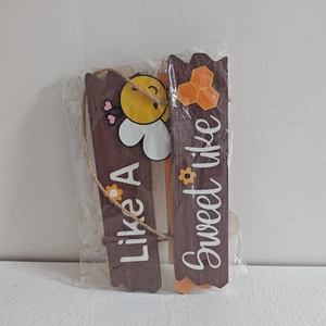 Dettaglio targa decorativa in legno con api e testo artistico Sweet Like