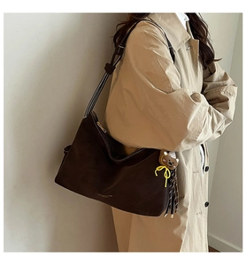 Detail der kaffeebraunen Shopper-Tasche mit weißen Nähten und Teddybär-Anhänger
